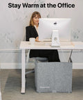 Woman using Silent Personal Warmer with Thermostat under desk, energy efficient for warm legs and feet in office setting.