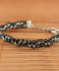 Close-up of a braided bracelet with brown, blue, and green threads woven using a round kumihimo disk for jewelry making.