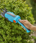 Person using Cordless Hedge Trimmer And Grass Shears For Easy Lawn Edges And Shrubs Battery Powered Handheld Electric Garden Tool