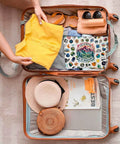 Open suitcase packed with clothes and a hiking makeup bag showcasing colorful graphics, ideal for nature lovers and campers.