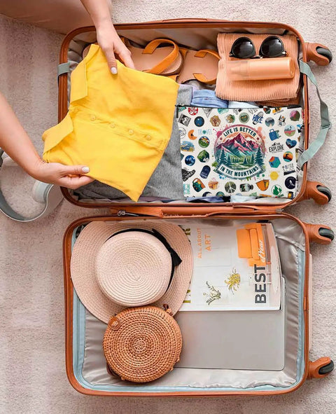 Open suitcase packed with clothes and a hiking makeup bag showcasing colorful graphics, ideal for nature lovers and campers.