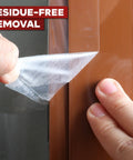 Person peeling Transparent Window Weather Stripping Tape 2 Inch By 30 Yard Pack Three No Residue Insulation Seal for a door.