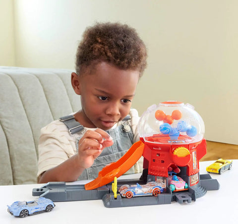 Child playing with Hot Wheels Downtown Candy Shop Playset With 1:64 Scale Die-Cast Donut Shaped Car and gumball machine