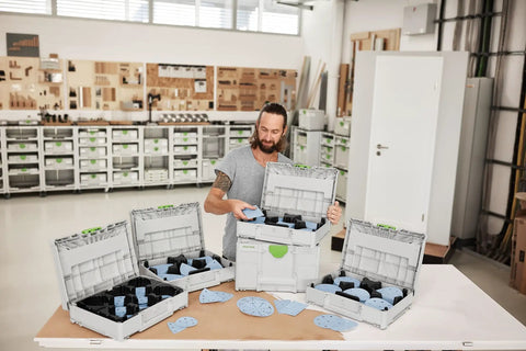 Person organizing Granat DTS Delta Abrasive Systainer GR Set For VOC Paints And Hard Surfaces in workshop with open Systainer kits