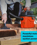 User using the No Sweat Three Gallon Wet Dry Shop Vacuum Portable Corded to clean wood debris on a workshop floor.