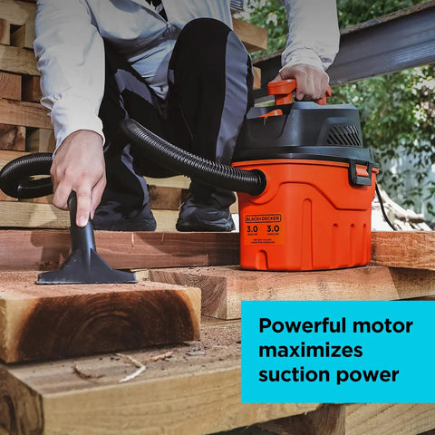 User using the No Sweat Three Gallon Wet Dry Shop Vacuum Portable Corded to clean wood debris on a workshop floor.