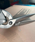 Close-up of Long Cut Tin Snips With Offset Design For Straight And Curved Cuts In Sheet Metal Projects on cardboard surface