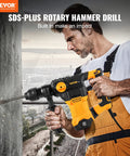 Side view of orange and black VEVOR SDS-Plus rotary hammer drill with auxiliary handle drilling into concrete