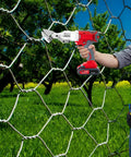 21V Brushless Cordless Sheet Metal Shear With Two Batteries And 360 Degree Pivoting Head cutting wire mesh in a garden setting.