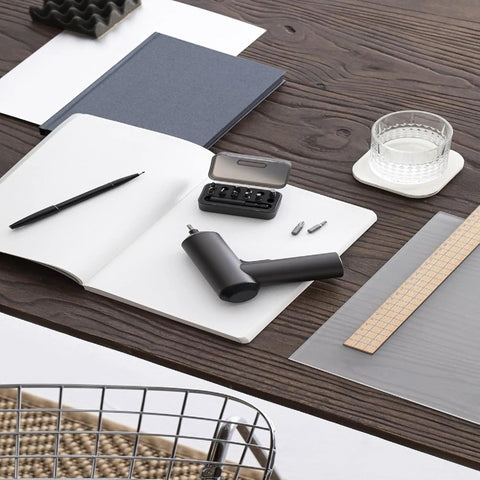Cordless Screwdriver With USB C Charging, 3.6V 2000mAh Battery on desk, includes 12 S2 steel bits in a box, placed next to a notebook.