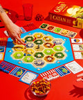 Premium Island Settlement Building Strategy Board Game For Families And Crew Ages 10 Plus Master Resource Trading Expand Territories For An Epic Hella Fun Tabletop Adventure with game board and snacks.