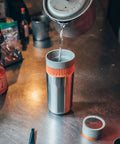 All In One Portable Coffee Maker With Vacuum Pressure Brew Hand Powered On The Go Coffee Brewer Insulated Stainless Steel Travel Mug 10 Ounce Thermo Cup Quick Fresh Brew For Commutes And Outdoors with water being poured on a counter.