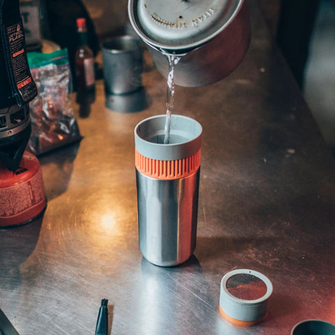 All In One Portable Coffee Maker With Vacuum Pressure Brew Hand Powered On The Go Coffee Brewer Insulated Stainless Steel Travel Mug 10 Ounce Thermo Cup Quick Fresh Brew For Commutes And Outdoors with water being poured on a counter.