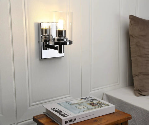 Super Cool Vintage Style One Light Wall Sconce With Clear Glass Shade And Metal Base In Chrome Perfect For Creating An Industrial Vibe In Your Bathroom Vanity Mirror Bedroom Hallway Kitchen Hardwired Wall Mount Light Fixture mounted on white wall.