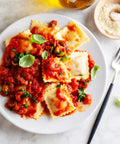 Plate of homemade ravioli with tomato sauce made using Ravioli Cutter and Pastry Wheel for Fresh Pasta and Dough That Seals Crimps and Cuts Perfectly With 18 10 Stainless Steel Build Awesome for Homemade Ravioli Pastry Crusts and Dough