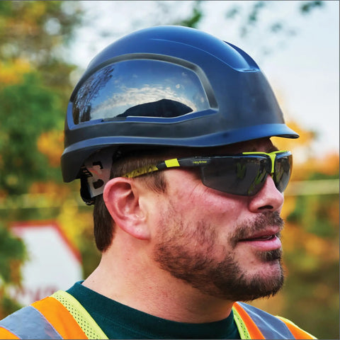 Sick Clear Vision Transition Safety Glasses With Anti Fog Coating And Scratch Resistant Lenses Featuring Adjustable Non Slip Fit For Legit All Day Comfy ANSI Certified Protection on a worker wearing a hard hat outdoors.