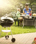 Family enjoying meal beside Premium 22 Inch Charcoal Grill Portable Outdoor BBQ Grill With Durable Plated Steel Grates in garden