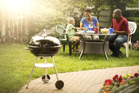 Family enjoying meal beside Premium 22 Inch Charcoal Grill Portable Outdoor BBQ Grill With Durable Plated Steel Grates in garden