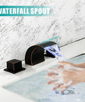 Person washing hands under Waterfall LED Bathroom Faucet In Oil Rubbed Bronze, 8 Inch Widespread Vanity Sink Faucet With Two Handles, 3 Hole Installation, Roman Tub Style, Color Changing Water Temperature Light