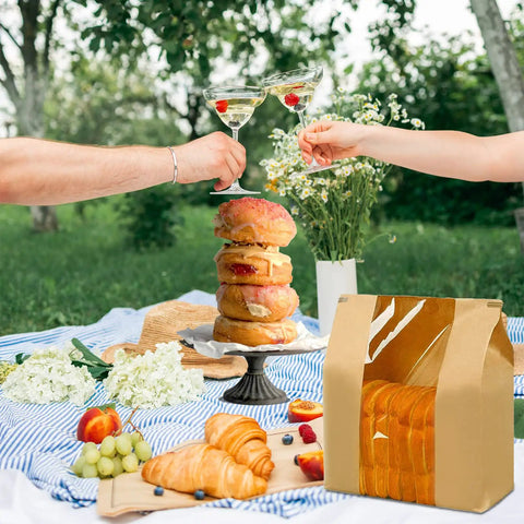 Picnic scene with 100 Pack Large Paper Bread Bags With Tin Tie Tab Lock Clear Front Window and baked goods, outdoors.
