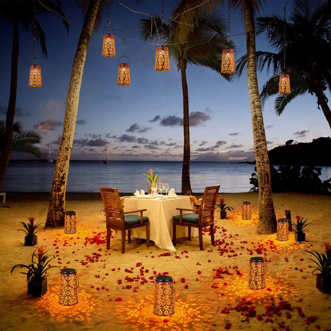 Two Pack Solar Hanging Lanterns Outdoor Lights With IP55 Waterproof Rating Retro Metal Decor illuminating beach dinner scene.