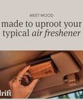 Front view: Drift teak wood car air freshener block held in hand inside a car, with drift logo.