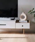 White modern console table with decorative vase and books next to a large TV, featuring sleek lines and minimalist decor style.