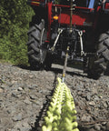 Heavy Duty Triple Chain Shrub And Clump Remover Tool With Four Foot Pulling System attached to tractor on rocky ground