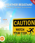 Kickass Caution Watch Your Step Signs 2 Pack 10 X 7 Inch Rust Free Reflective Aluminum Safety Plaque Weatherproof Warning Sign in grass.