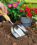 Heavy Duty Garden Trowel With Stainless Steel Blade And Ergonomic Ash Wood Handle being used for soil loosening in a garden