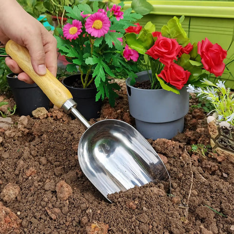 Heavy Duty Garden Trowel With Stainless Steel Blade And Ergonomic Ash Wood Handle being used for soil loosening in a garden