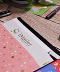 Close-up of pink polka dot Thank You poly mailers 12 x 15.5 inch self-seal shipping bags with inner liner on wooden table.