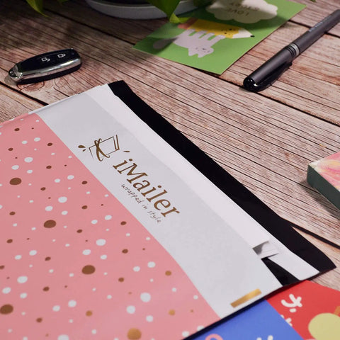 Close-up of pink polka dot Thank You poly mailers 12 x 15.5 inch self-seal shipping bags with inner liner on wooden table.