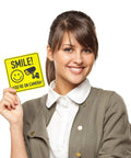 Smile Youre On Camera Signs 7 By 7 Inch 8 Pack Security Notice Stickers For Home Office And Outdoors Deterrent Alerts Visitors Theyre On Camera And Helps Keep Your Family And Property Safe With This Easy To Install Sign Set. 7x7 vinyl sign held by woman