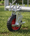 Six Inch Heavy Duty Tube Gate Wheel With Brake Red Galvanized Steel Caster Built Tough To Carry 450 Pounds close-up on grass