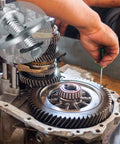 Go-kart clutch bolt kit components on minibike transmission; technician using screwdriver near gears.