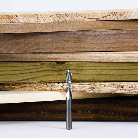 SpeTool 1/4 in upcut spiral router bit with 1/4 in shank, solid carbide, standing in front of plywood boards