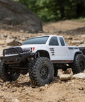SCX24 Base Camp 4x4 Rock Crawler RC truck in white on rocky terrain, equipped with Spektrum 2.4GHz radio system