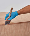 Person applying Water Based Pre Stain Wood Conditioner For Even Stain, 1 Quart, Clear Finish on wooden surface with brush