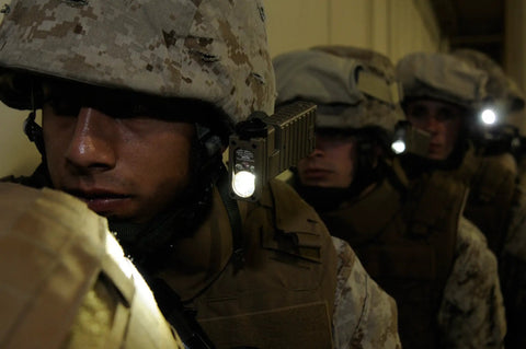 Military personnel using Sidewinder 55-Lumen LED Aviation Waterproof Flashlight with helmet and MOLLE mount in a dim hallway.