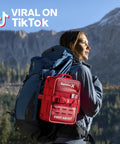 Red SurviveX first aid kit attached to a blue hiking backpack (side view)