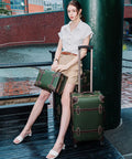 Woman seated with vintage 3 piece luggage set hardside lightweight spinner suitcases with under seat train case in army green