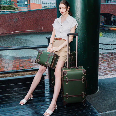 Woman seated with vintage 3 piece luggage set hardside lightweight spinner suitcases with under seat train case in army green