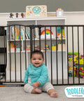 Toddler sitting in front of 3 In 1 Arched Decor Metal Superyard Play Yard 6 Panel Playpen baby gate extra wide fence 30 inches tall