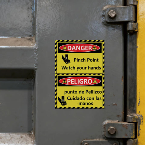 Installed bilingual Danger Pinch Point Watch Your Hands sticker set warning labels on metal door in a workshop.