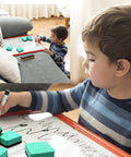 Child using Magnetic Whiteboard Erasers 48 Pack For Kids And Classrooms, green 2x2 inch erasers, writing on a board at home.