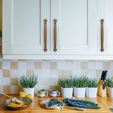 Antique Brass Cabinet Pulls 3-3/4 Inch 96mm 10 Pack Solid Zinc Alloy on white kitchen cupboards above a wooden countertop with herbs.