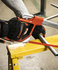 12 Inch Fast Tension Hacksaw With Dual Material Handle, sawing metal pipe on yellow workbench, ergonomic front grip visible