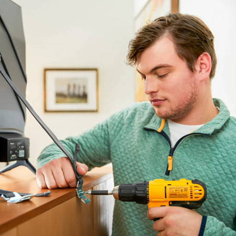 Person installing TV And Furniture Safety Straps 53 Inch Long Universal Mounting Straps For TVs To Wall Or Furniture using drill