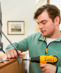 Man installing Universal TV Security Straps Four Pack For Wall Furniture And Anti Tip Configurations Secure Your TV To The Wall Or Furniture